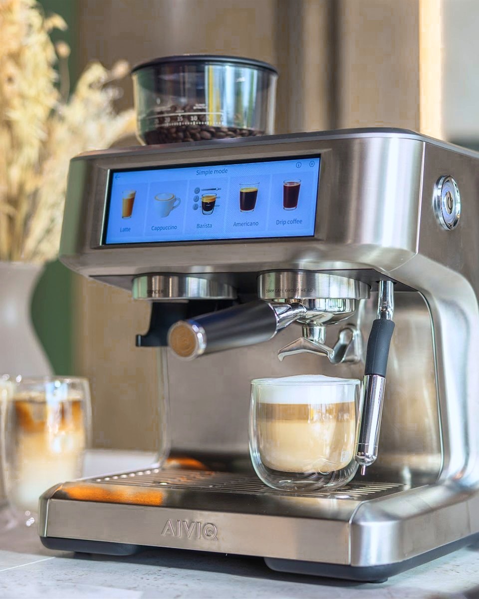 AIVIQ Aspire Expert mit Touchscreen auf einer Küchenarbeitsplatte, daneben zwei Latte macchiato